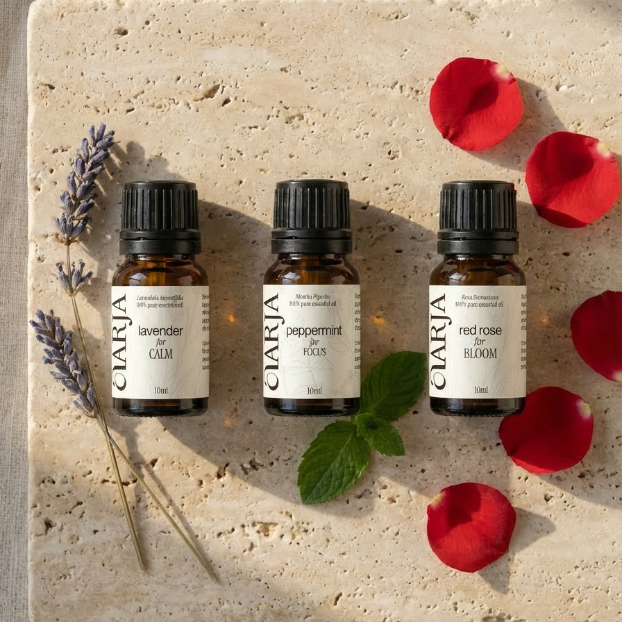 Three essential oil bottles on a stone surface with lavender, peppermint, and red rose petals.